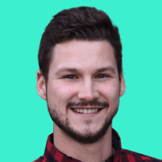 Smiling man named Evan Dunn with short dark hair and a beard, wearing a red checkered shirt against a teal background