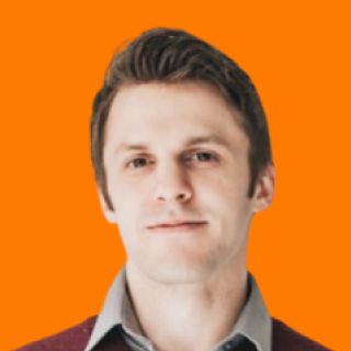Evan Dunn with short hair and a neutral expression against an orange background, wearing a collared shirt and sweater.